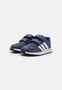 Baskets de sport bleues et marines avec des rayures blanches, des sangles à boucle, une tige texturée et une semelle en caoutchouc pour une meilleure adhérence.