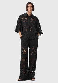Zwarte kant twee-delige set met een losse, korte mouwen shirt en bijpassende broek met bloemmotieven en een relaxte pasvorm.
