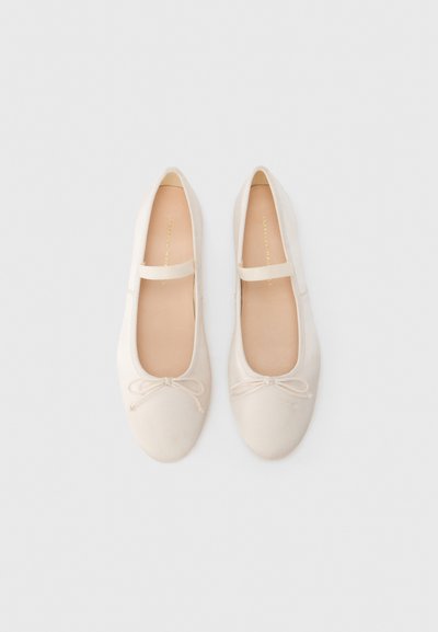 Λευκά μπαλαρίνες με απαλό ύφασμα στο επάνω μέρος, μαλακή σόλα και διακοσμητικό φιόγκο στο μπροστινό μέρος. Διαθέτουν λουράκι πάνω από το κουτεπιέ.