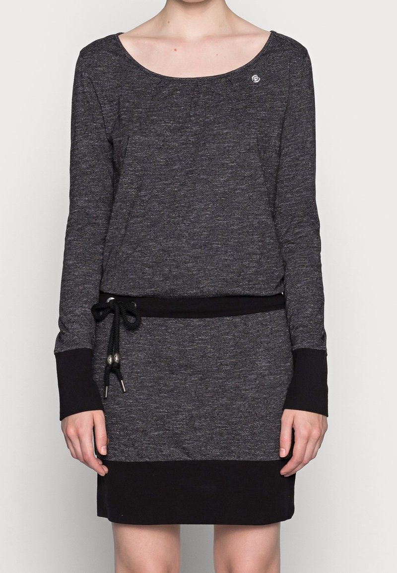 Femme portant une robe à manches longues gris foncé avec poignets noirs, ceinture à nouer et ourlet noir, debout devant un fond uni.
