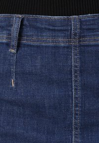 Denim skjørt i mørkeblått med en glatt tekstur, som har synlige sømmer, en frontlomme og en tettsittende livlinje.