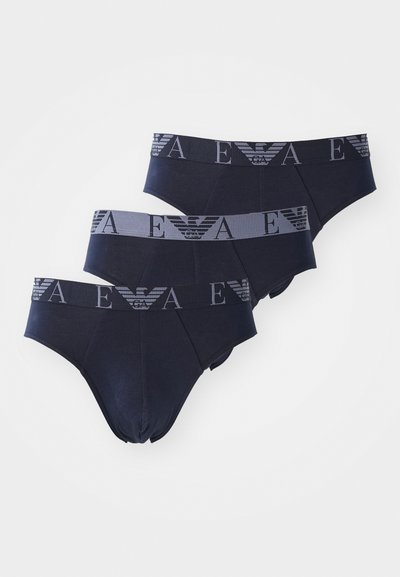 Três pares de boxers azul-marinho, fabricados com um tecido suave. Cada um tem uma faixa contrastante com um logótipo e um padrão.