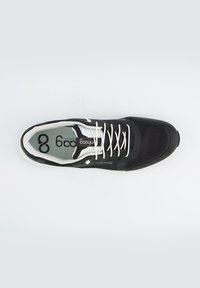 Chaussure de sport noire avec une tige en mesh, des lacets blancs et un capuchon de protection texturé. Comprend une semelle intérieure gris clair avec un logo. Semelle extérieure blanche lisse.