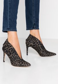 Zapatos de tacón alto con estampado de leopardo, diseño de punta afilada y corte en forma de V, con una textura de tela suave y tacón de aguja delgado.