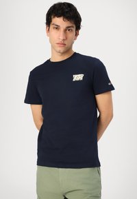 T-shirt in cotone blu navy con maniche corte, presenta un logo bianco sul petto. Include un piccolo logo di accento sulla manica.