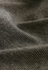 Tejido de punto que presenta una textura ajustada y con patrón de hilos en gris oscuro y gris claro alternos, creando un diseño a cuadros clásico.