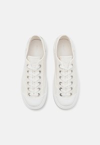 Witte canvas sneakers met een ronde neus, vetersluiting aan de voorkant, zilveren oogjes en een contrasterende witte rubberen zool. Gladde textuur en eenvoudig ontwerp.