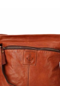 Borsa in pelle marrone con una tasca con zip orizzontale e una toppa con logo cucita che presenta un'ancora e il testo "HARBOUR 2nd."