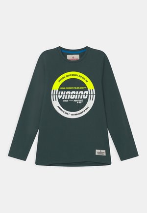 Mørkegrøn langærmet skjorte med rundt gult og hvidt logo med teksten "Vingino" og ekstra mærketekst centreret på brystet.