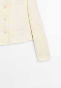 Veste texturée de couleur crème avec manches longues et quatre boutons assortis sur le devant, montrée de la taille jusqu'à l'ourlet inférieur.