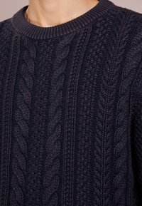 Marineblauer gestrickter Pullover mit strukturiertem Zopfmuster und geripptem Rundhalsausschnitt. Hergestellt aus dickem Garn, das Wärme und Komfort bietet.
