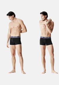 Caleçons boxers noirs avec un waistband élastique blanc et marine arborant le logo "pierre cardin" ; modèle montré sous deux angles, mettant en valeur la coupe et le style.