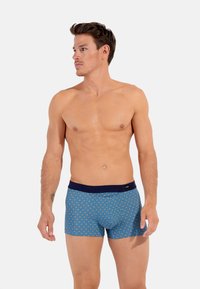 Boxer shorts blu con motivo, dotati di una vita blu navy, che presentano un design geometrico in rosso e bianco. Realizzati in un tessuto morbido e elasticizzato.