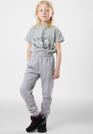 Graues Grafik-T-Shirt mit einem Stern-Design, kombiniert mit hellgrauen Sweatpants. Schwarze Sportschuhe mit rosa Akzenten. Einfaches, lässiges Outfit.