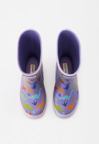 Lasten violetit kumisaappaat, joissa on värikkäitä dinosauruskuvioita ja laventelin väriset sisäosat, kuvattuna ylhäältä valkoista taustaa vasten.