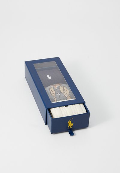 Boîte bleu marine avec fenêtre transparente affichant des chaussettes. Comprend un design gris sur une paire et blanc avec logo. La boîte est équipée d'une languette en ruban.