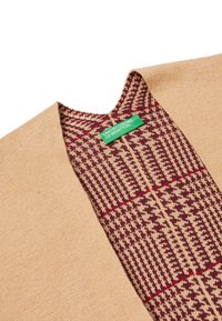 Beige cardigan se strukturovaným vzorem v burgundské a krémové barvě. Má výstřih do V a zelenou nálepku s nápisem "United Colors of Benetton."