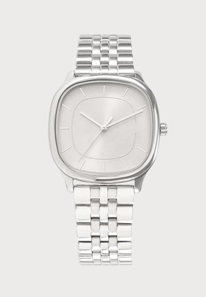 Reloj de pulsera plateado con esfera cuadrada, marcadores de hora mínimos, agujas plateadas y una correa metálica enlazada.