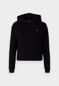 Svart cropped hettegenser laget av myk tekstil. Har lange ermer, en stor hette, og et lite logo-patch på brystet. Glatt tekstur.