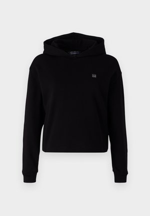 Čierny skrátený mikina s kapucňou vyrobená z mäkkej látky. Má dlhé rukávy, veľkú kapucňu a malú nášivku s logom na hrudi. Hladká textúra.