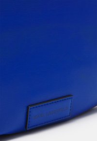 Borsa a tracolla in ecopelle blu con superficie texturizzata, design minimalista e etichetta nera impresso con "KARL LAGERFELD."
