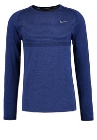 Niebieska, sportowa koszulka z długim rękawem, wykonana z fakturowanej tkaniny, z okrągłym dekoltem, logo Nike i otworami na kciuki w mankietach.