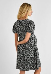 Abito nero floreale con maniche a puff corte, caratterizzato da un motivo di fiori bianchi, una vestibilità comoda e una gonna arricciata che si ferma sopra il ginocchio.