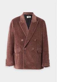 Veston en velours côtelé marron croisé avec de larges revers, quatre boutons assortis en tissu et deux poches à rabat à l'avant.