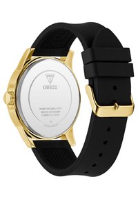 Montre en acier inoxydable doré avec un bracelet en silicone noir. Présente le logo de la marque, des détails sur la résistance à l'eau et un design de bracelet texturé.