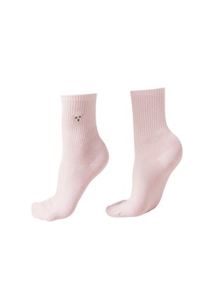 Chaussettes rose pâle côtelées avec un petit visage de chien blanc brodé sur le côté extérieur d'une chaussette, portées sur des pieds inclinés.