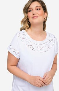 Camiseta de algodón blanca con mangas cortas que presenta bordado de ojales florales alrededor del escote y los hombros para añadir textura y detalle.