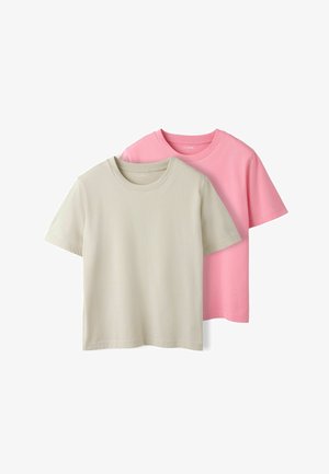 Deux T-shirts en coton uni, l'un beige superposé devant un rose, présentés sur un fond blanc.