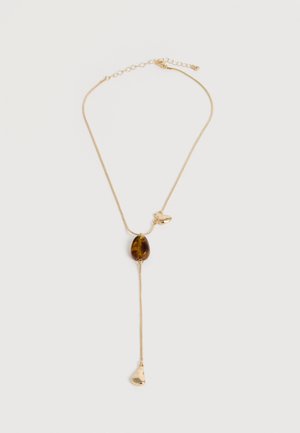 Collier chaîne délicate en or avec pierre centrale en ambre, petit charme en or à côté de la pierre et pendentif goutte d'or pendant sur fond blanc.