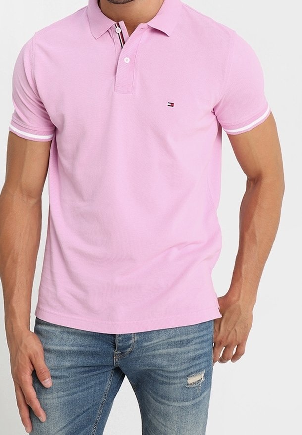 Chemise polo rose en coton, à coupe slim, avec un col et trois boutons, et un petit logo sur la poitrine. Associée à un jean.
