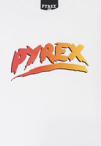 T-shirt bianca con un prominente logo multicolore "PYREX" in rosso e arancione con un design a pennellate. Stile classico con colletto rotondo.