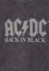Black cotton t-shirt featuring a grey graphic print of "AC/DC Back in Black." The design includes bold, angular lettering with a lightning bolt.