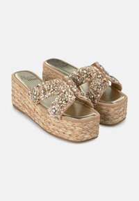 Sandali con zeppa beige dalla base in paglia intrecciata, impreziositi da accenti di cristallo scintillanti sulle cinghie incrociate e una comoda soletta metallica.