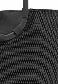 Schwarze Netz-Shopper-Tasche mit runder Oberseite, ausgestattet mit einem stabilen Griff und strukturiertem Material. Elastische Akzente sichern die Form.