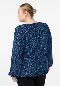 Navy blue blouse with light blue floral pattern, long sleeves, and a relaxed fit. Soft fabric with a rounded neckline and gathered shoulder details.