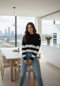 Czarnobiały sweter w paski z okrągłym dekoltem, ozdobiony guzikami na ramieniu, zestawiony z wysokim stanem niebieskich jeansów.