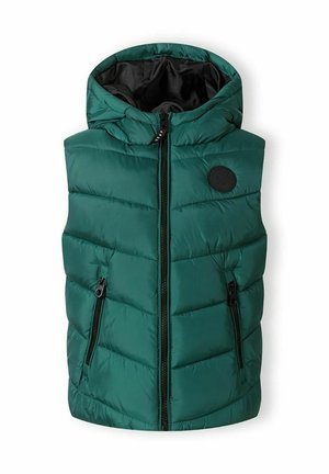 Veste matelassée verte sans manches avec capuche, fermeture éclair à l’avant, deux poches zippées et un patch rond noir sur la poitrine.