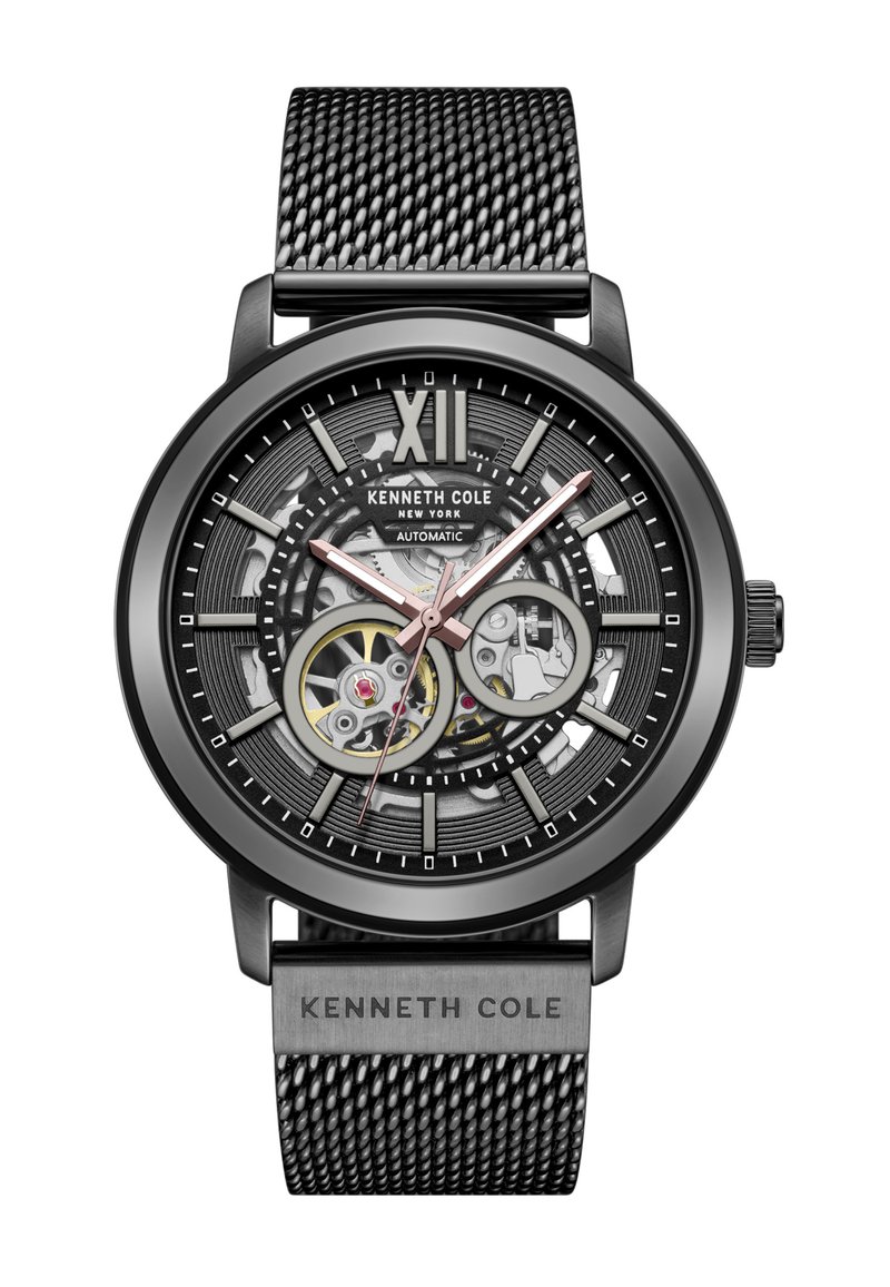 Reloj automático con correa de malla de acero inoxidable negro, diseño de fondo abierto, esfera negra y gris, acentos en oro rosa y grandes marcadores de hora.
