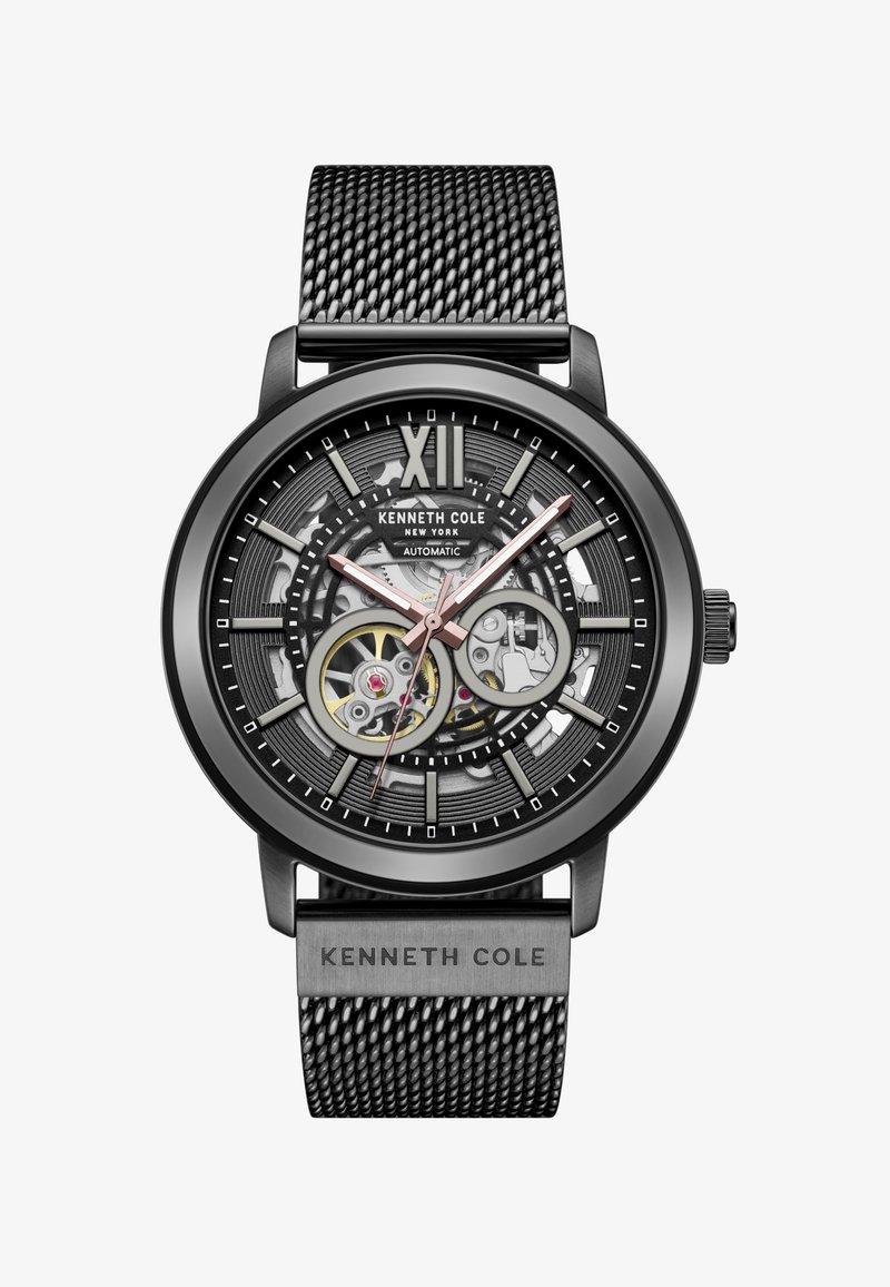 Reloj automático con correa de malla de acero inoxidable negro, diseño de fondo abierto, esfera negra y gris, acentos en oro rosa y grandes marcadores de hora.
