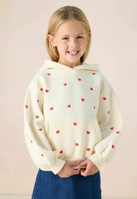 Crème hoodie met rode hartpatronen, lange mouwen, een trekkoordkap en een buidelzak, gecombineerd met een denim rok.