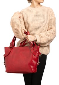 Rode leren tote bag met dubbele banden, gladde textuur en metalen accenten. De tas heeft een gestructureerde vorm en een ruime binnenkant.