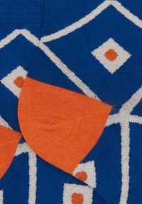 Calzini blu con un motivo geometrico in bianco e arancione. Il design include diamanti e forme con la punta e il tallone arancioni.