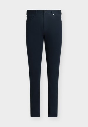 Pantalon bleu marine foncé coupe slim avec passants de ceinture, fermeture à boutons et zip à l'avant, et poches, sur un fond uni.