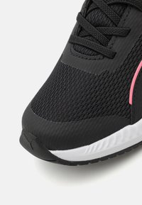 Chaussure de sport noire avec une tige en maille, un design texturé, des accents roses et une semelle intermédiaire blanche. Dotée de lacets et d'une semelle extérieure en caoutchouc pour une meilleure adhérence.