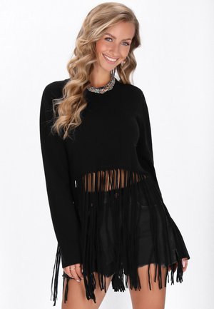 Zwart cropped sweater met lange franjes aan de onderkant, lange mouwen en een ronde hals, gecombineerd met hooggetailleerde zwarte shorts.