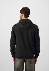 Felpa nera con cappuccio, maniche lunghe e polsini a coste, realizzata in un materiale morbido. Presenta una vestibilità rilassata e un design semplice.